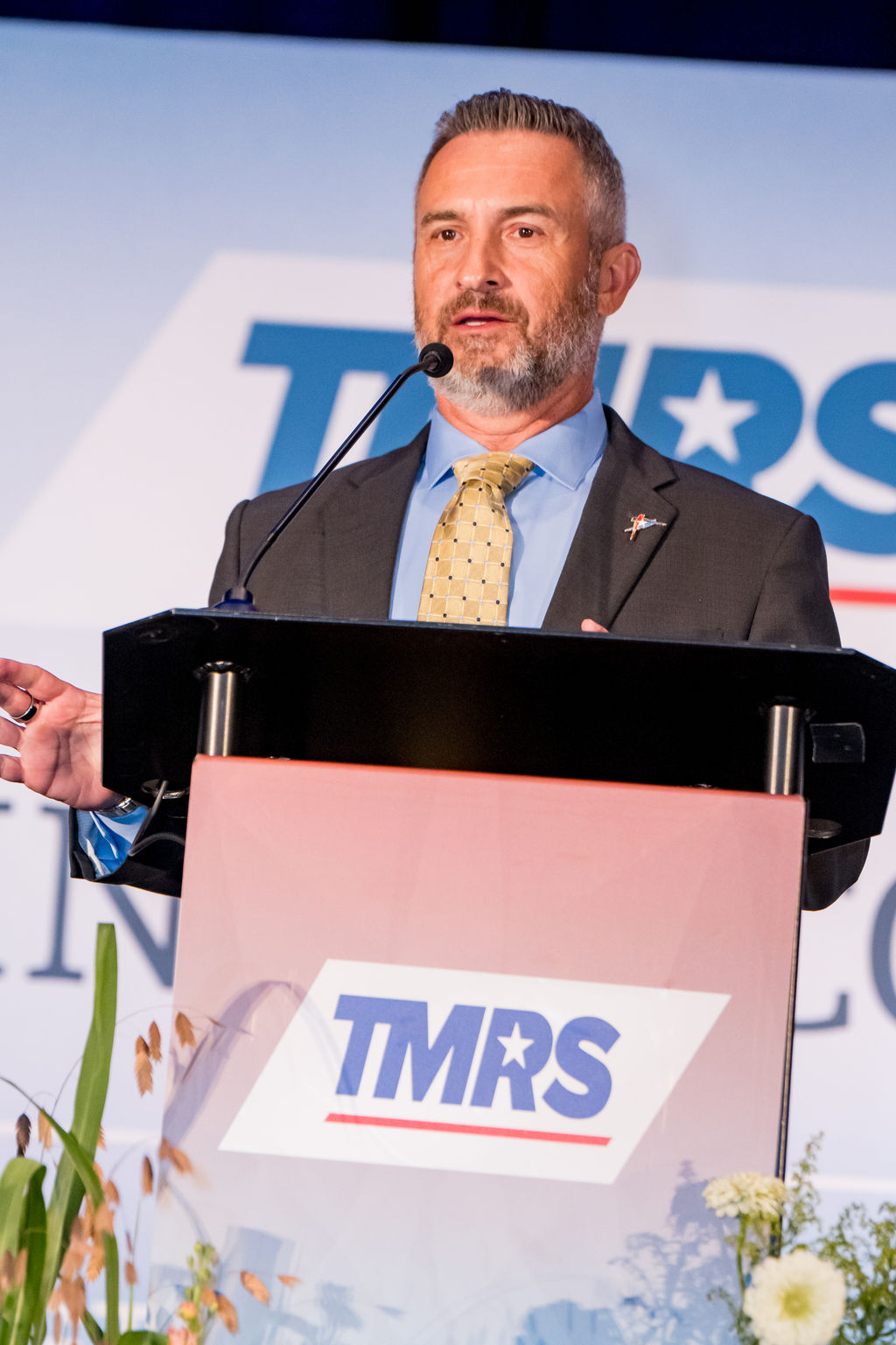 Speaker mid-remarks behind the TMRS branded podium