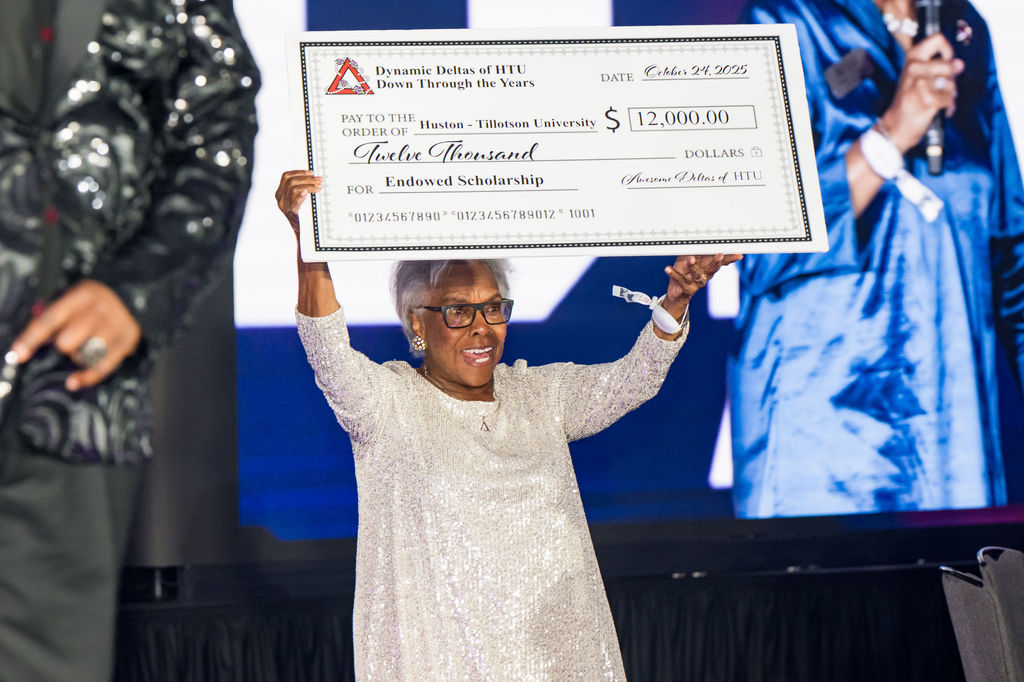 Donor presenting an oversized scholarship check on stage