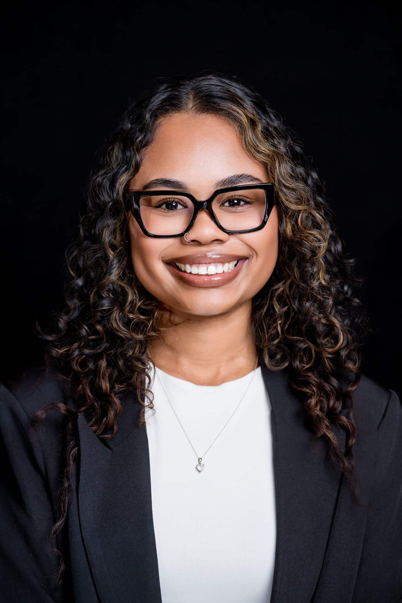 Studio headshot of a professional woman in a black blazer and glasses