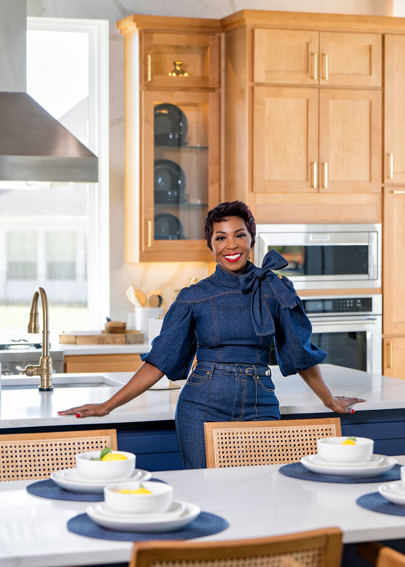 Business owner in denim standing at a bright kitchen island for a brand photo session