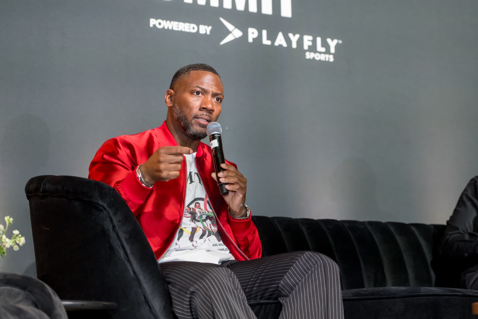 Panelist gesturing while speaking on a black velvet sofa