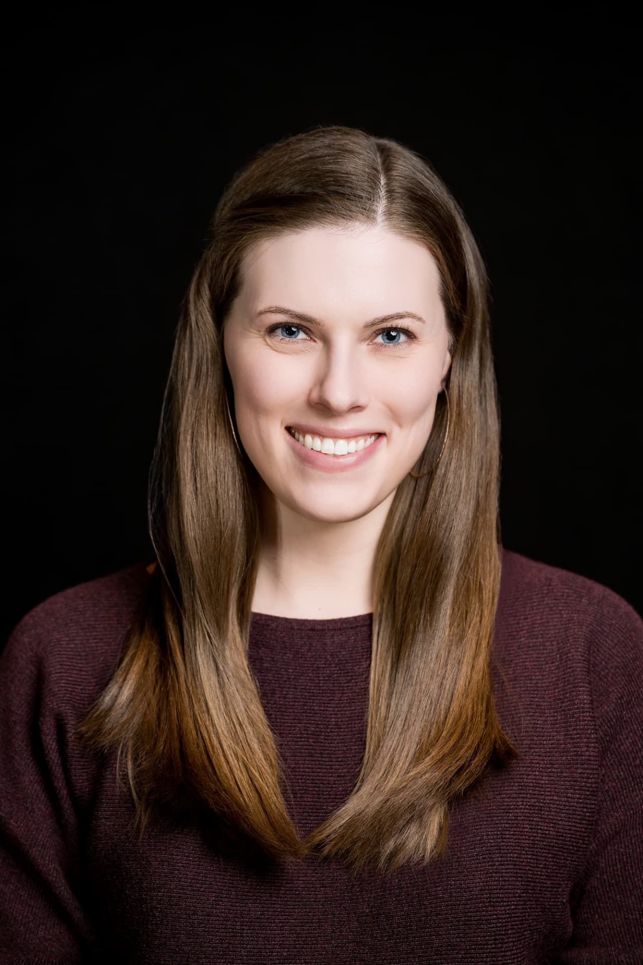 Studio headshot of a professional woman in a burgundy sweater