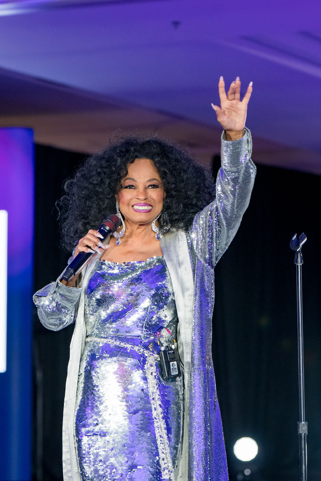 Headline performer in a sequined gown waving to the ballroom
