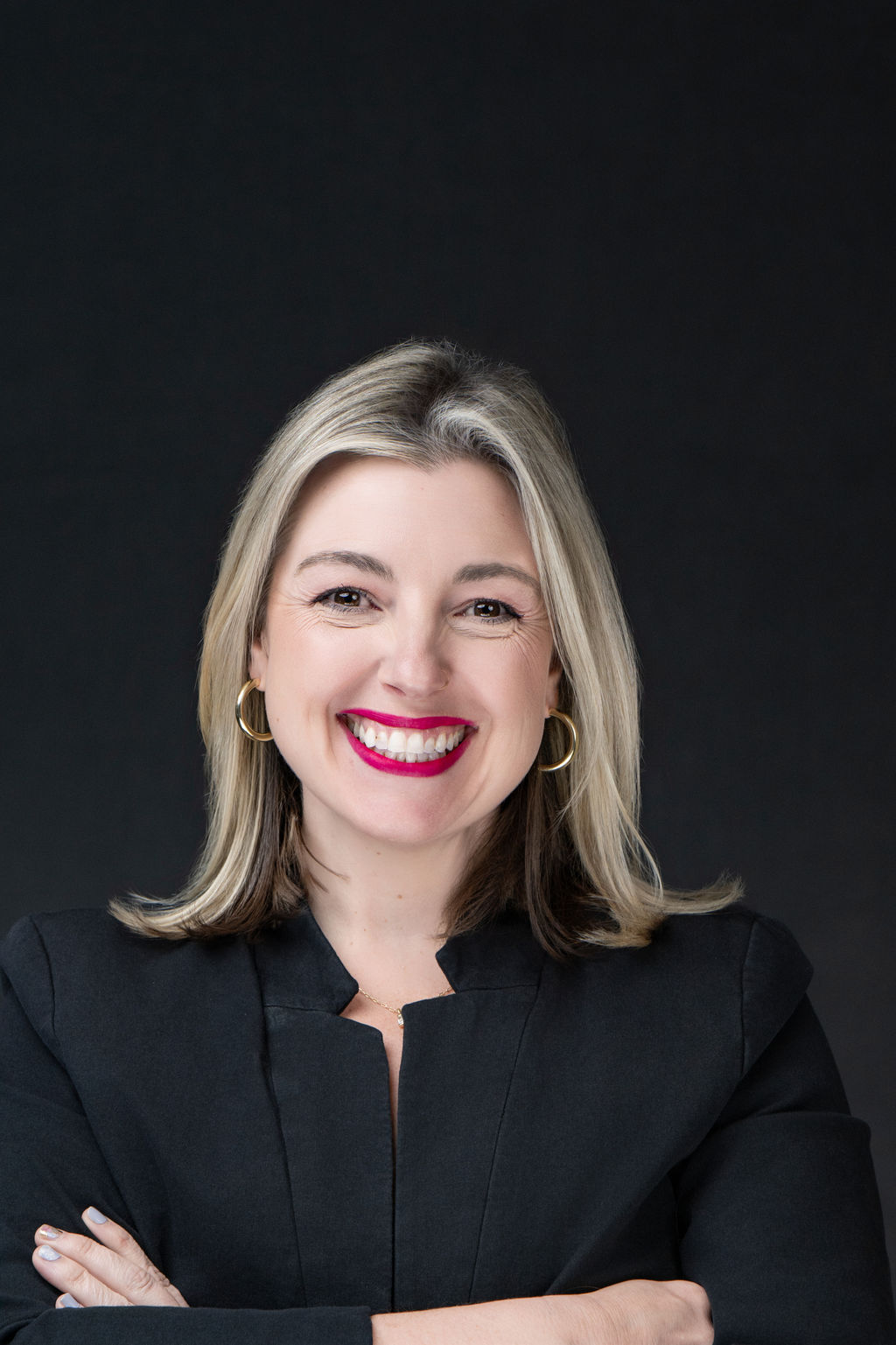 Studio headshot of a smiling woman with blonde hair in a black blazer