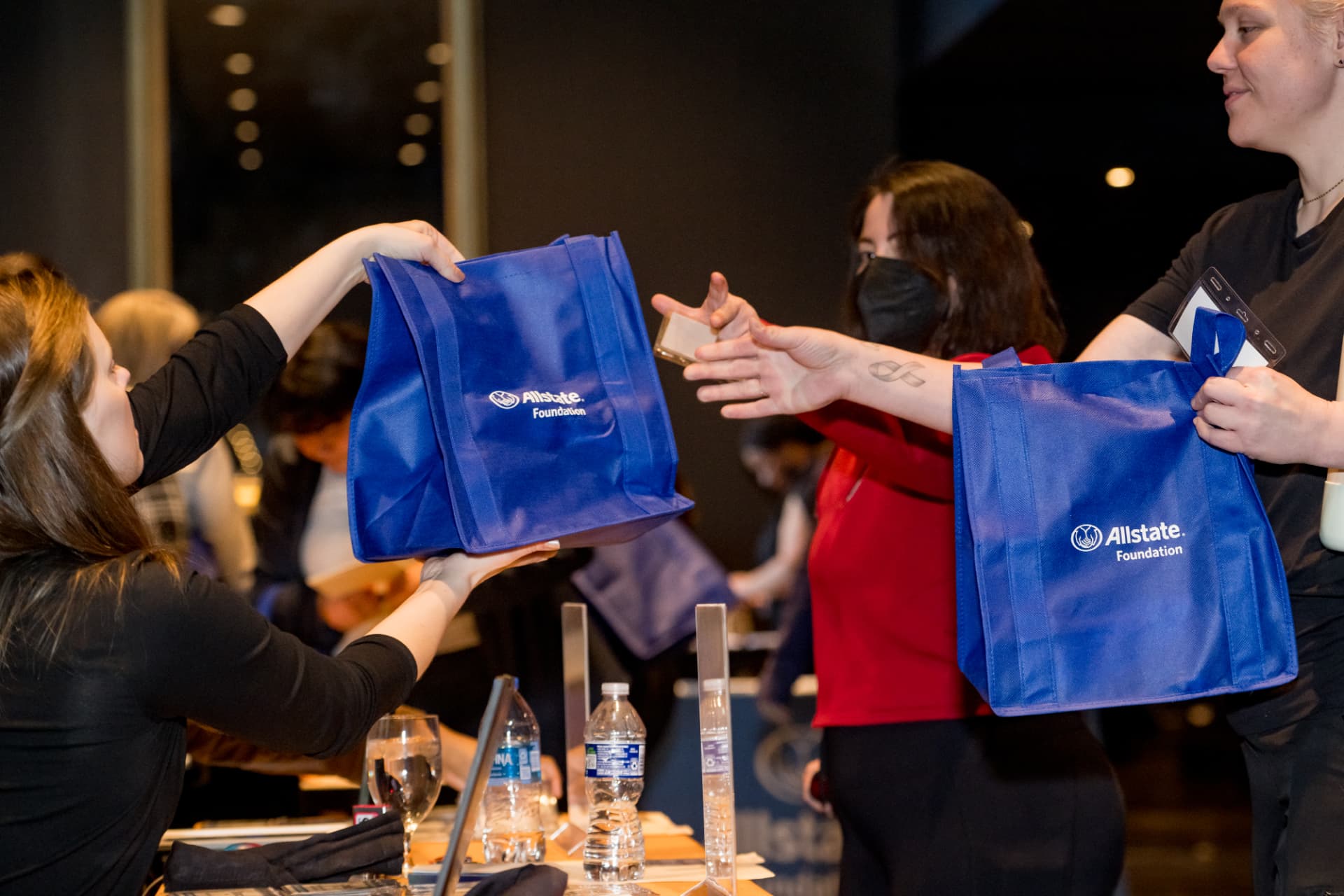 Volunteers handing out sponsor tote bags at an event registration table