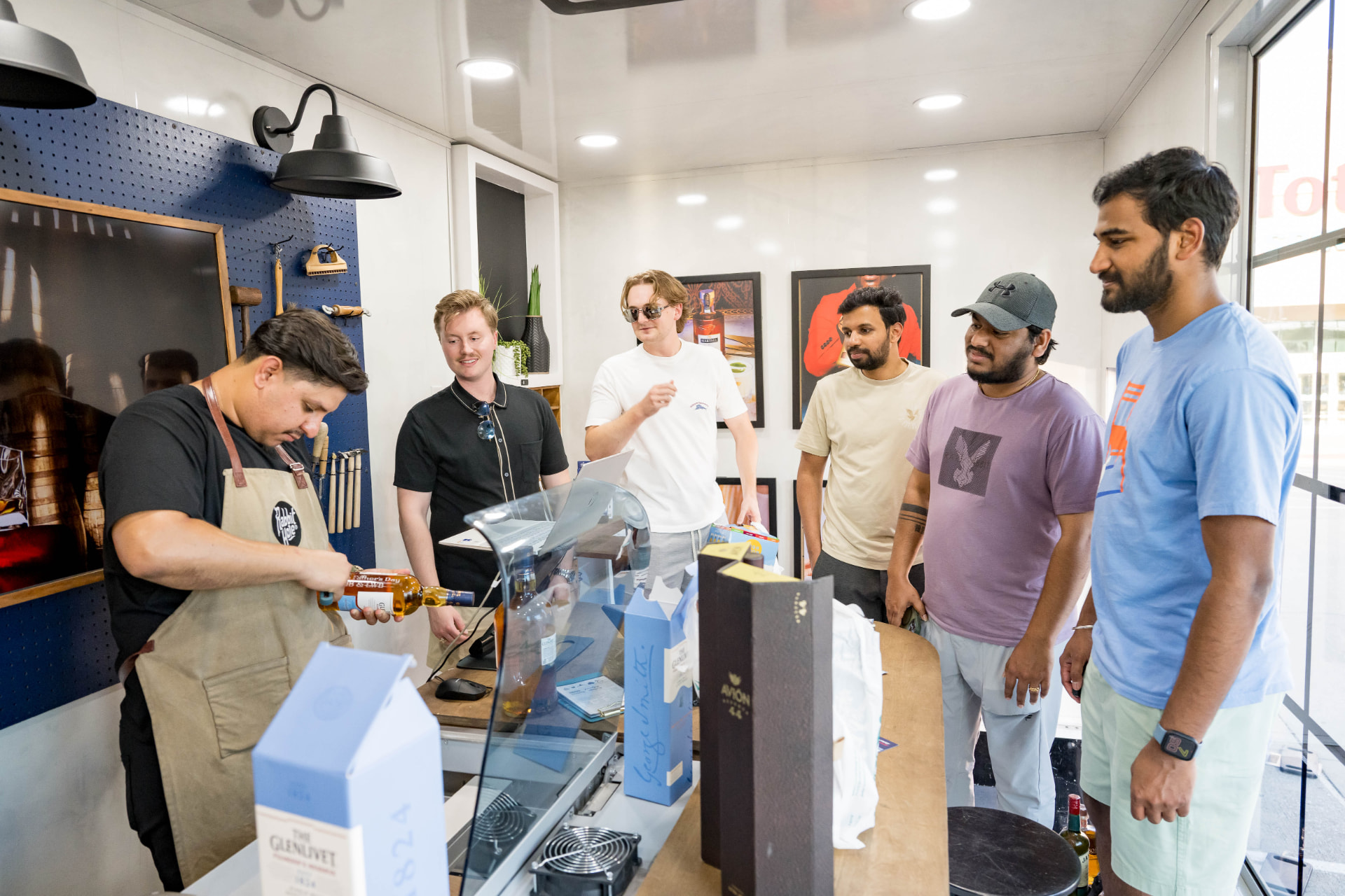Craftsman engraving a bottle as guests watch inside a brand experience space