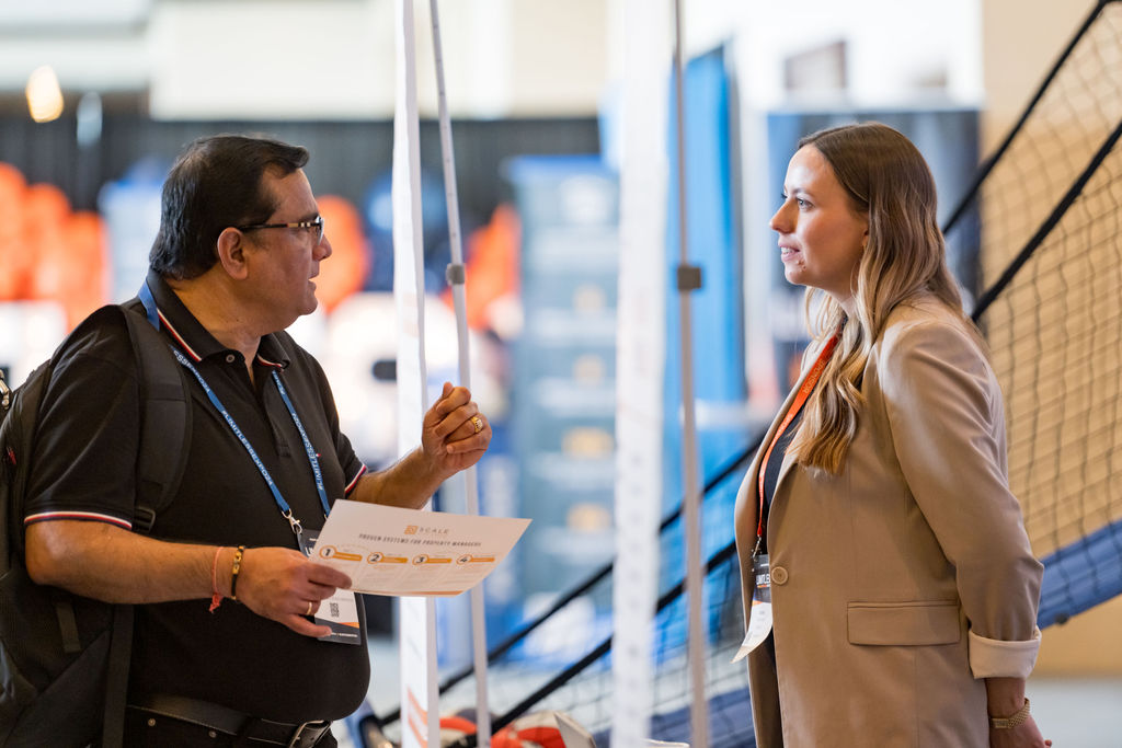 Exhibitor reviewing a handout with an attendee at Limitless Expo