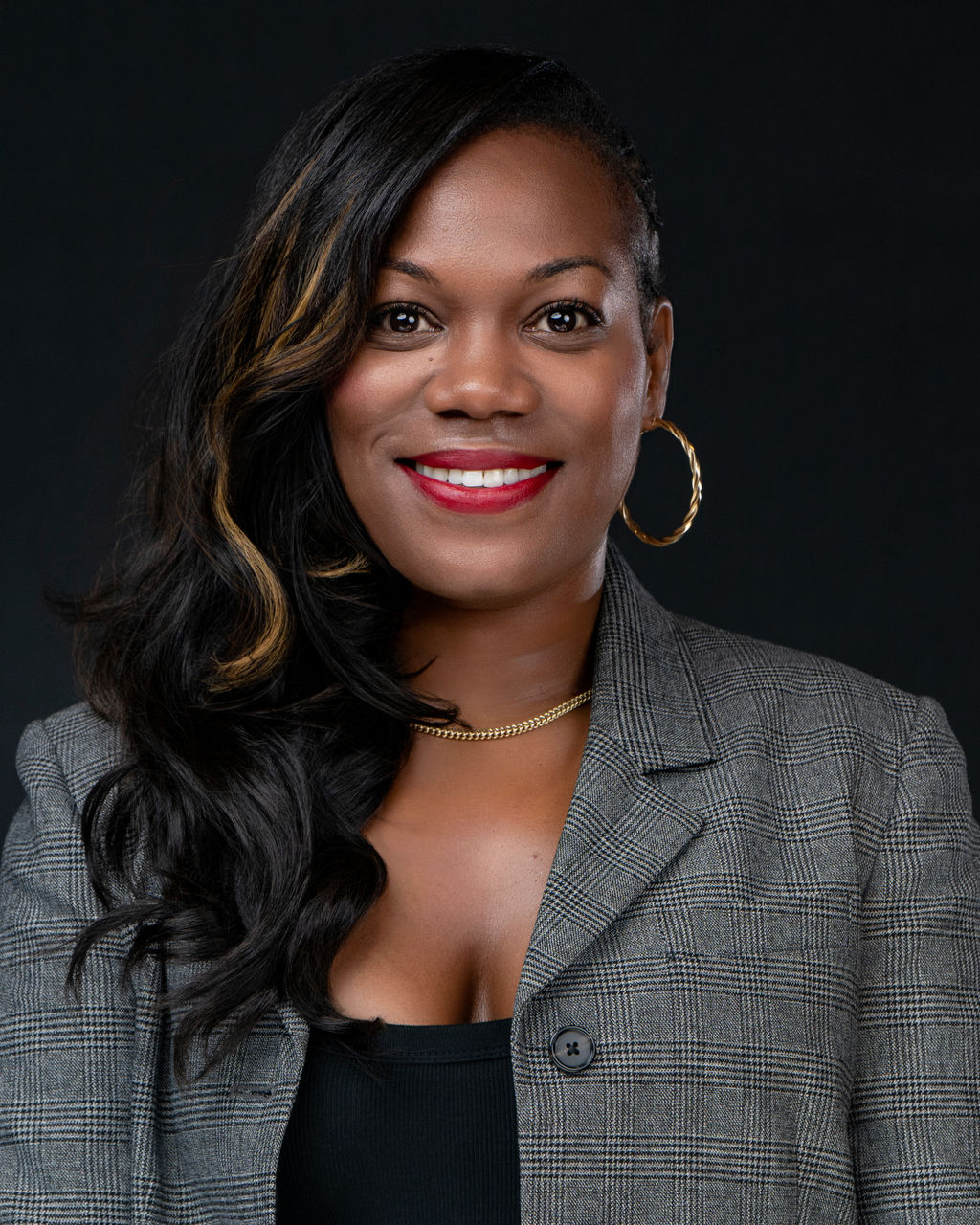 Studio headshot of a smiling woman in a grey plaid blazer