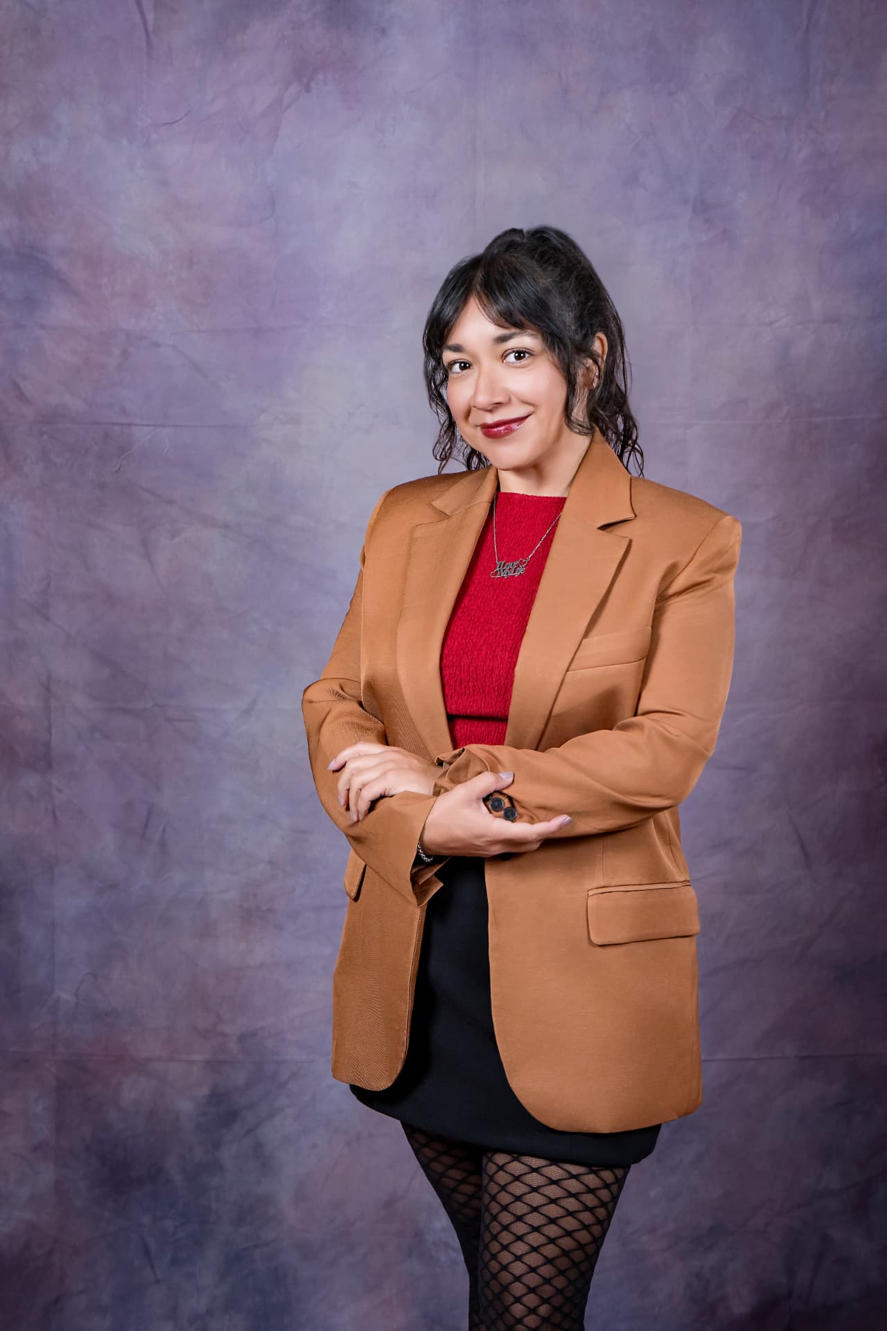 Studio portrait of a smiling woman in a camel blazer and red top
