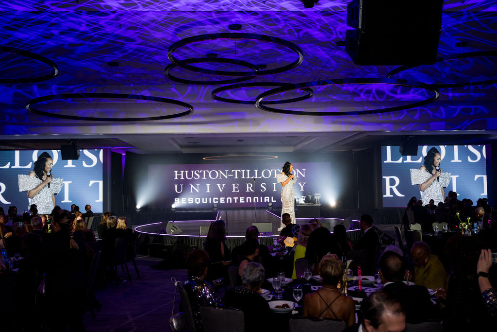 Host addressing the ballroom from the sesquicentennial stage