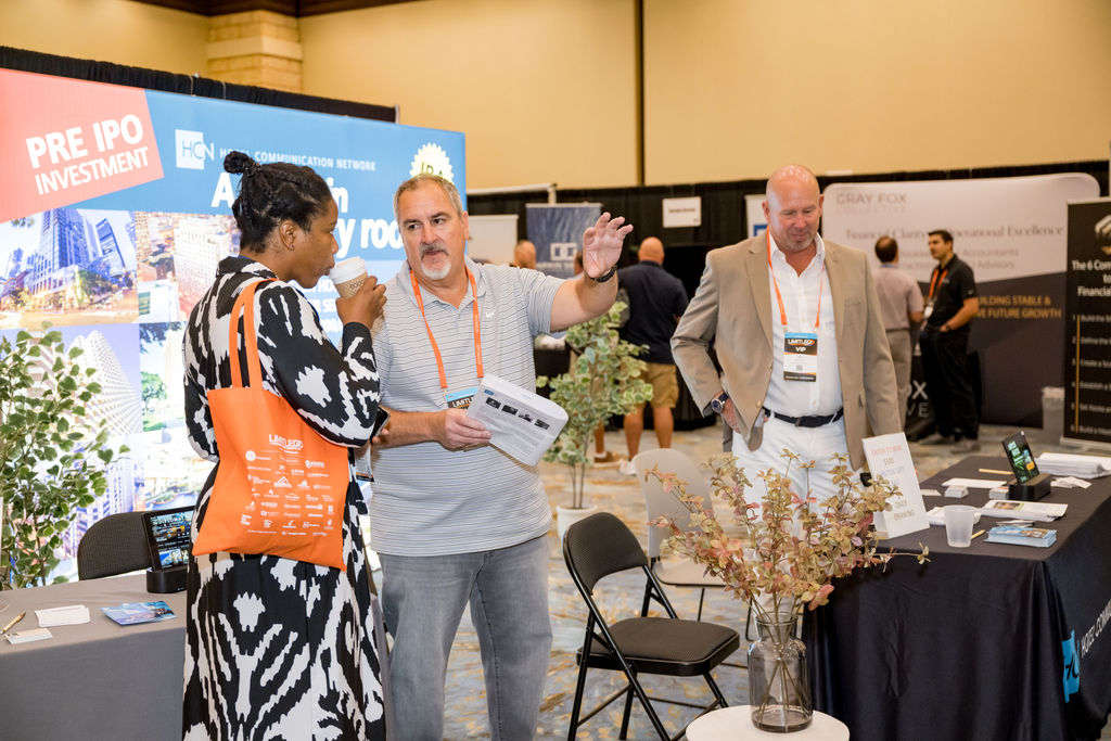Exhibitor speaking with attendees at a Limitless Expo trade show booth