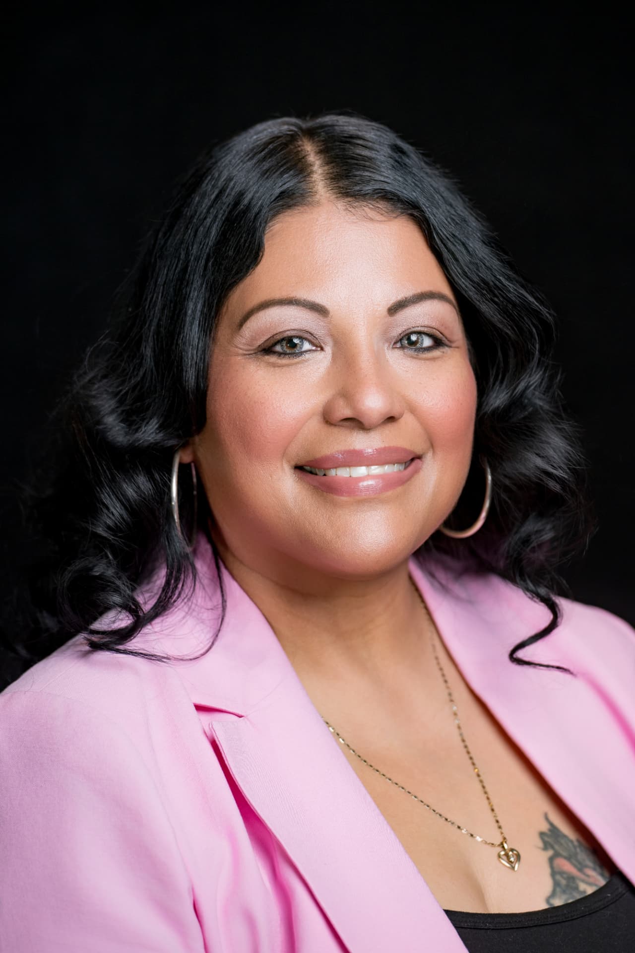 Studio headshot of a professional woman in a pink blazer