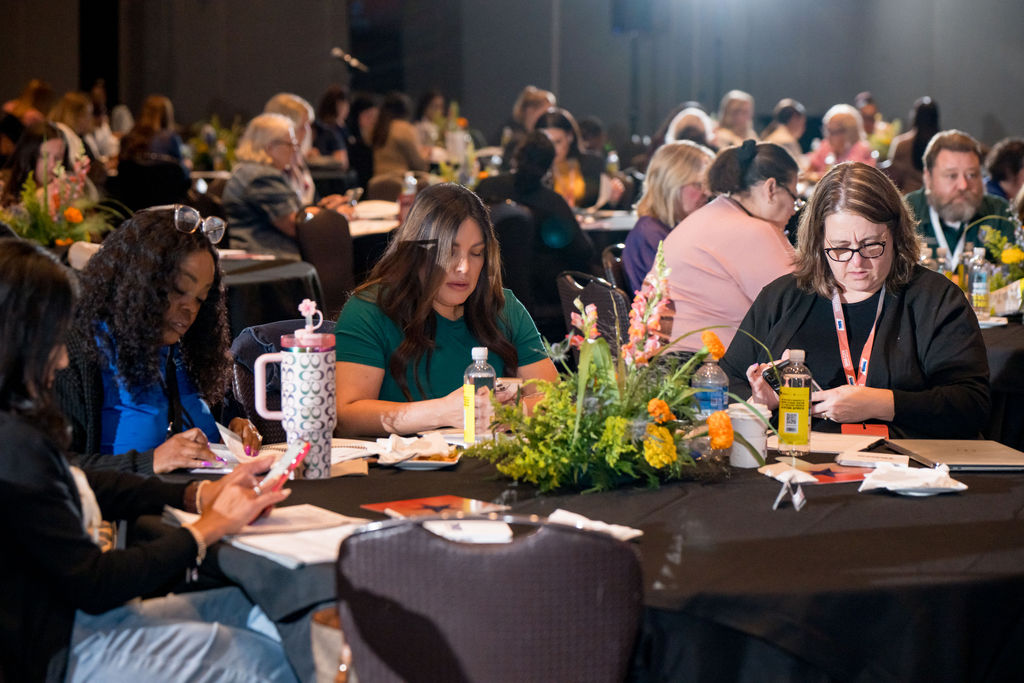 Attendees taking notes at their tables during a TMRS session
