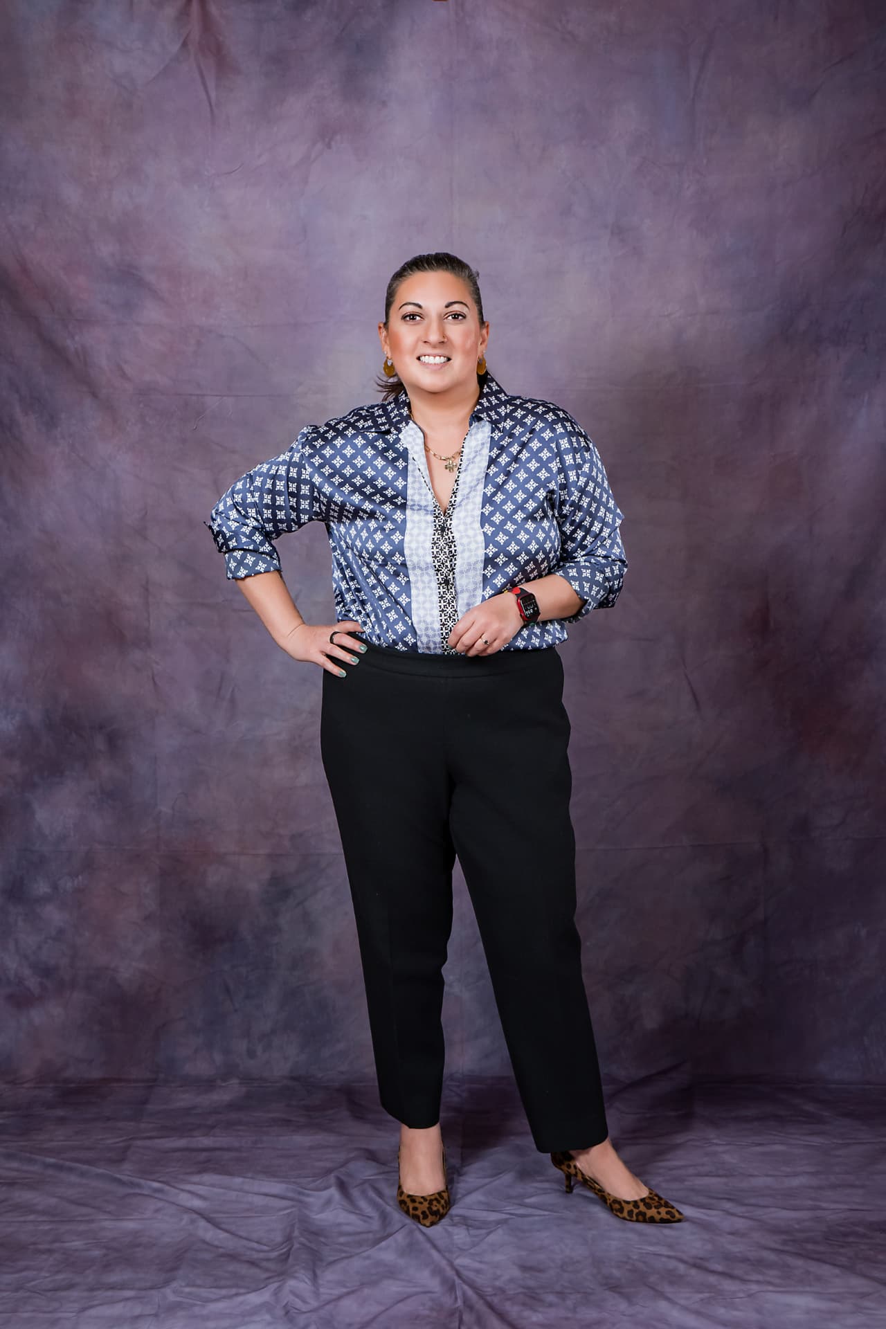 Full-length studio portrait of a smiling woman in a patterned blue blouse
