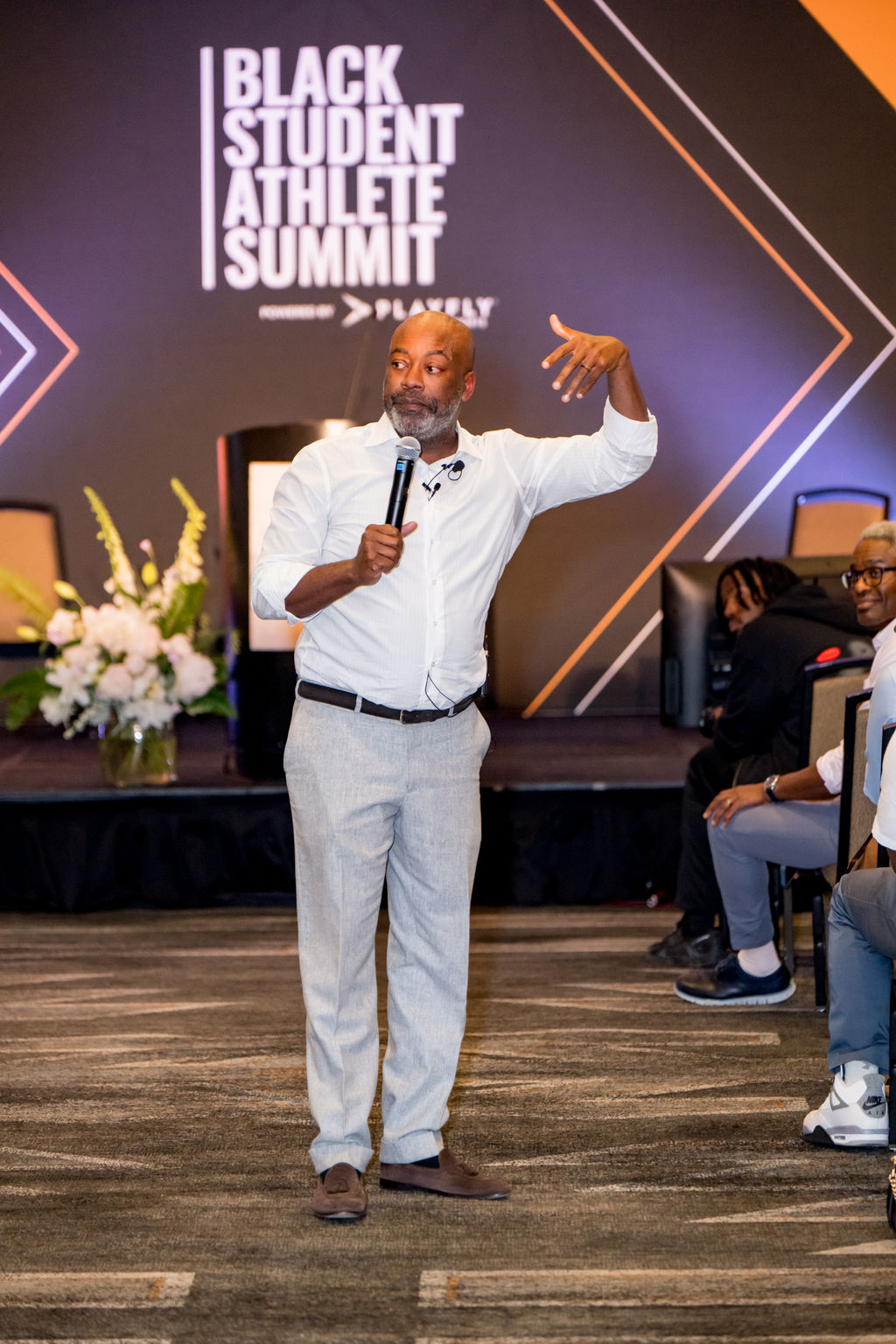 Speaker presenting in front of the Black Student Athlete Summit stage backdrop