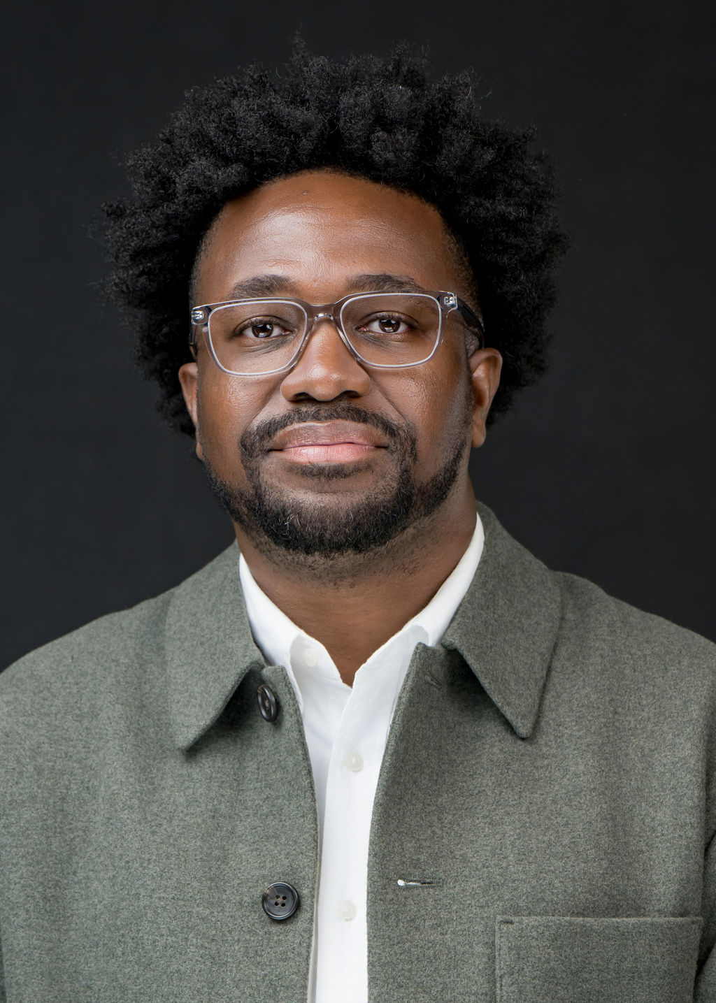 Studio headshot of a man with glasses in a green overshirt and white shirt