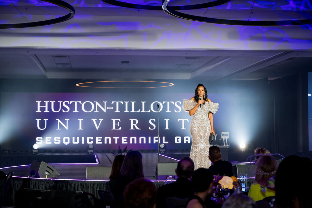 Host on stage in front of the Huston-Tillotson gala backdrop