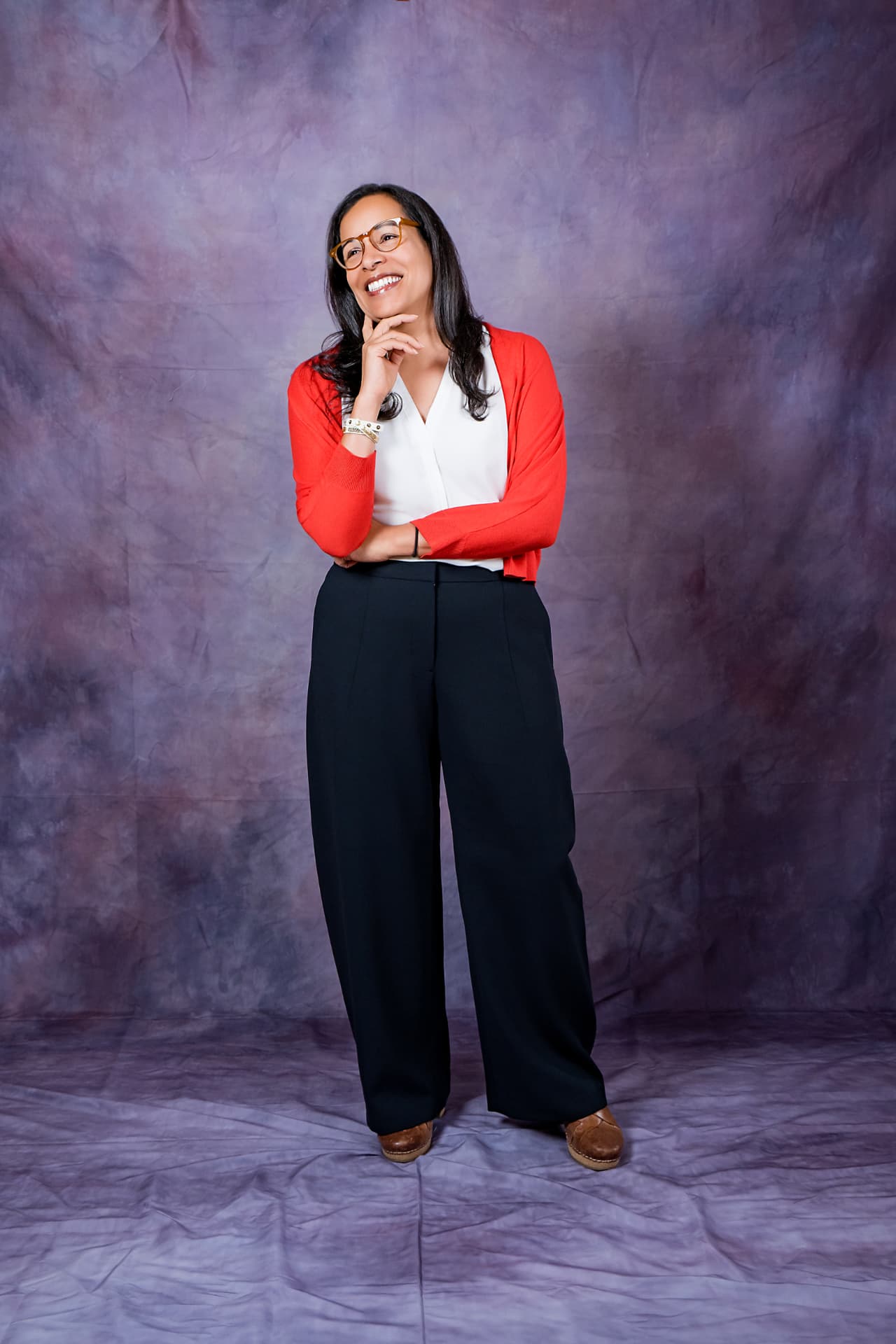 Full-length studio portrait of a smiling woman in a red cardigan