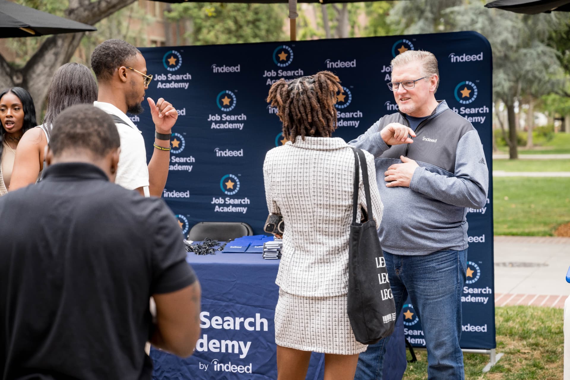 Indeed Job Search Academy representative speaking with attendees at a branded backdrop