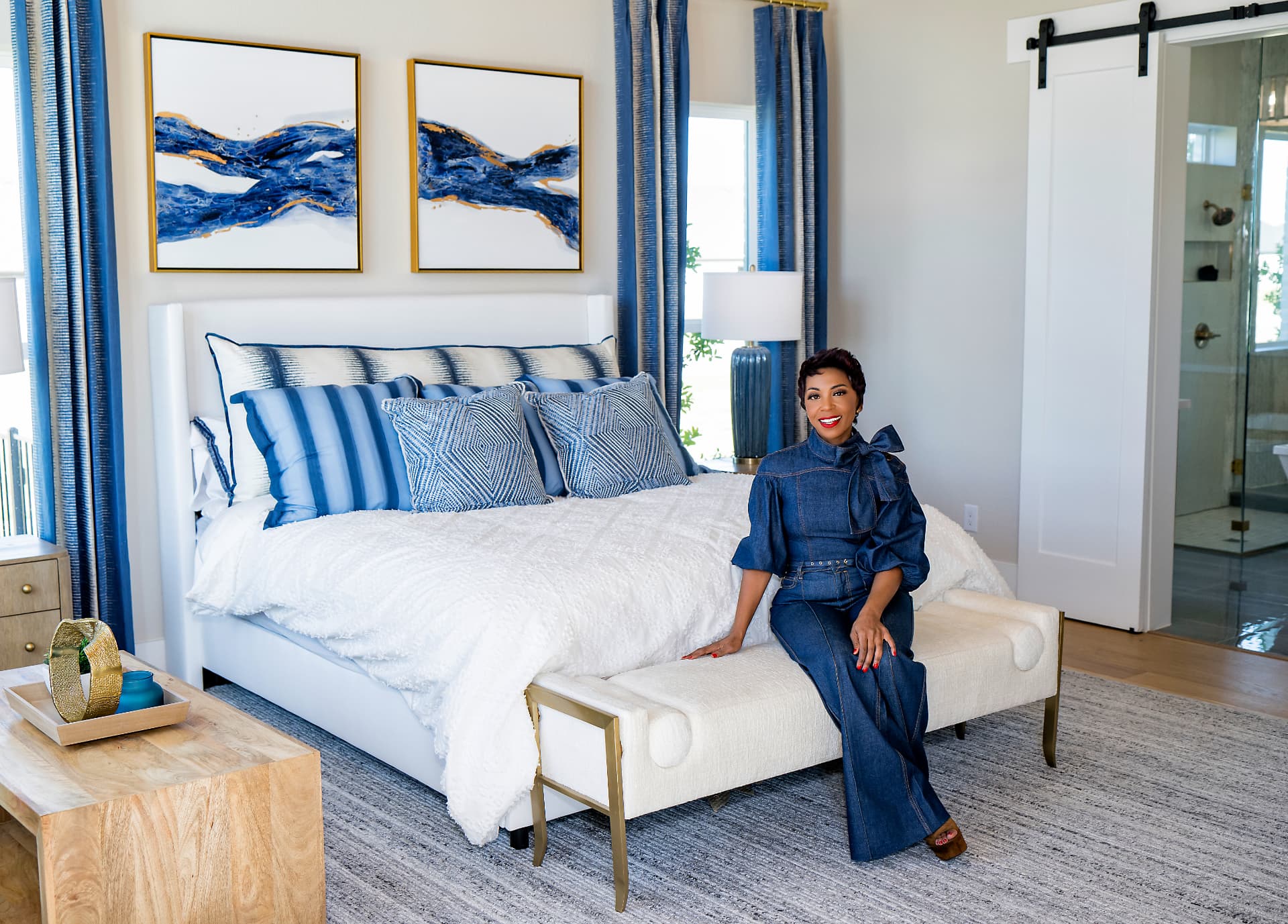 Brand founder seated at the foot of a bed in a styled interior feature