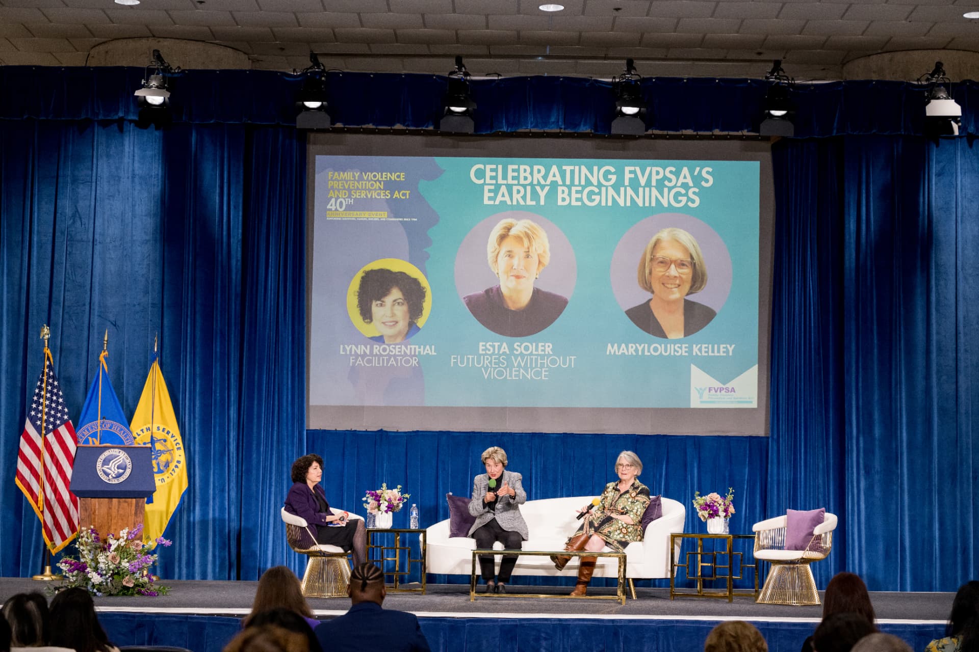 Panel conversation on stage in front of a large presentation screen