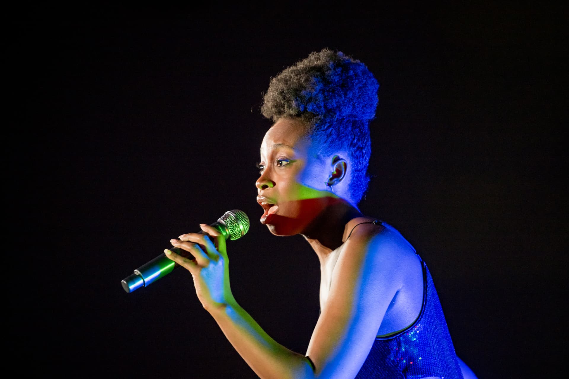 Vocalist performing under blue stage lighting