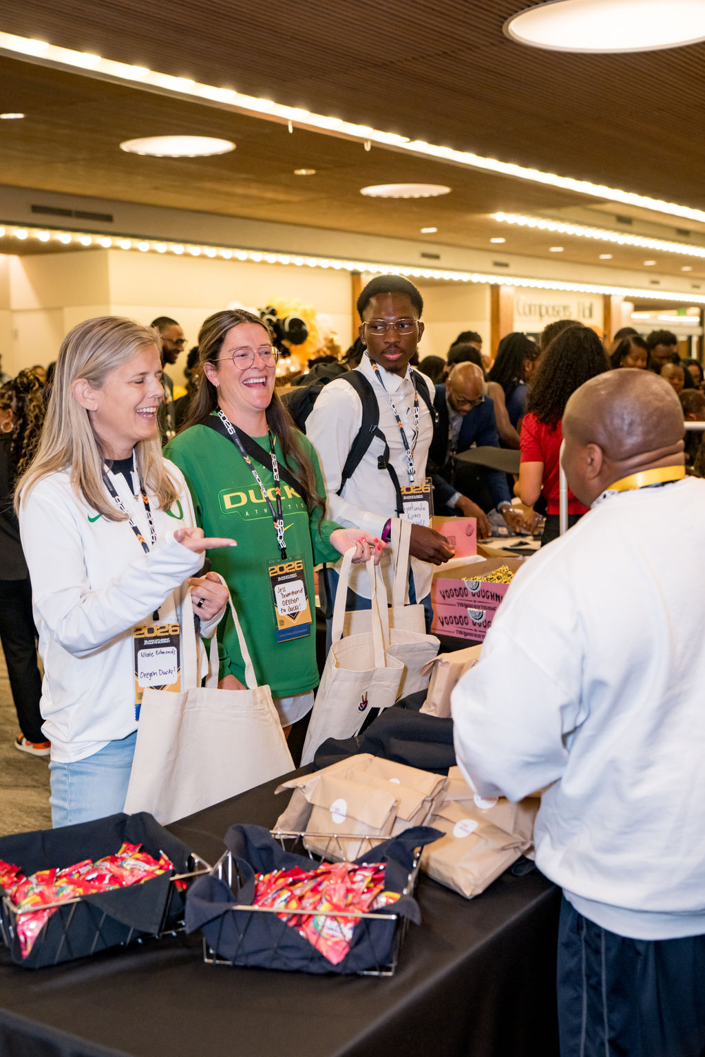 Attendees laughing while collecting tote bags at the BSA Summit welcome table