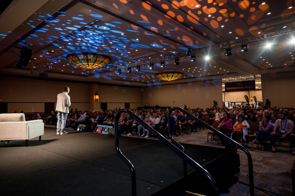 Stage-side view of a speaker addressing the Limitless Expo crowd