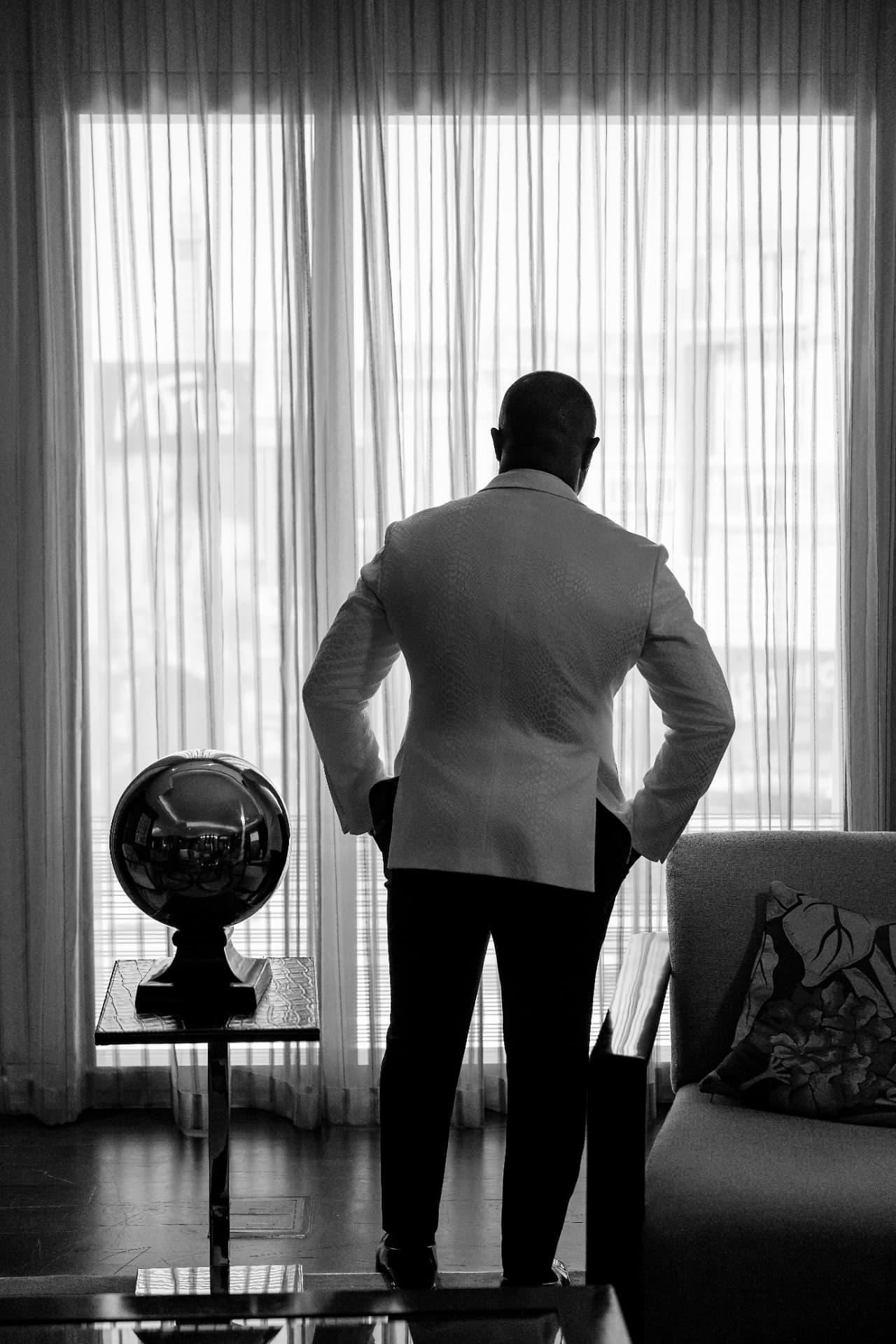 Black-and-white portrait of an executive in a white dinner jacket looking out a window