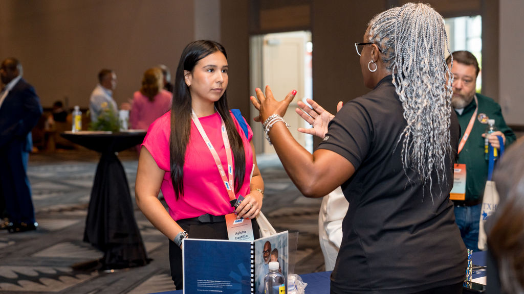 Attendees connecting at a TMRS exhibit table during a break