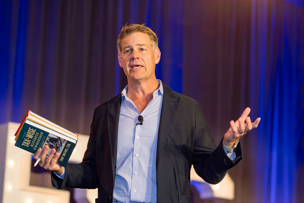 Author holding up his business book while presenting on the Limitless Expo stage