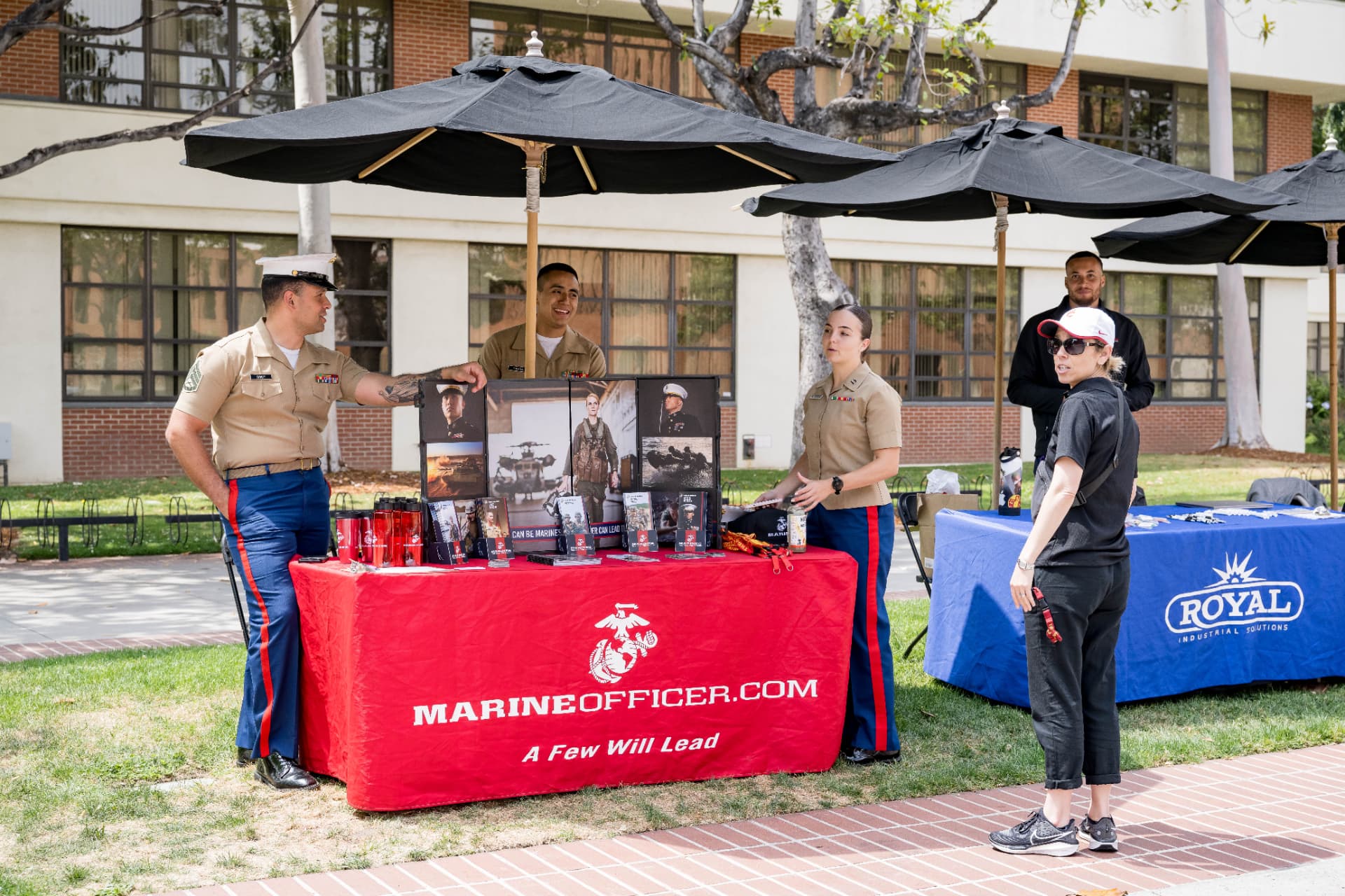 Marine Corps officer recruiters speaking with a guest at their expo table