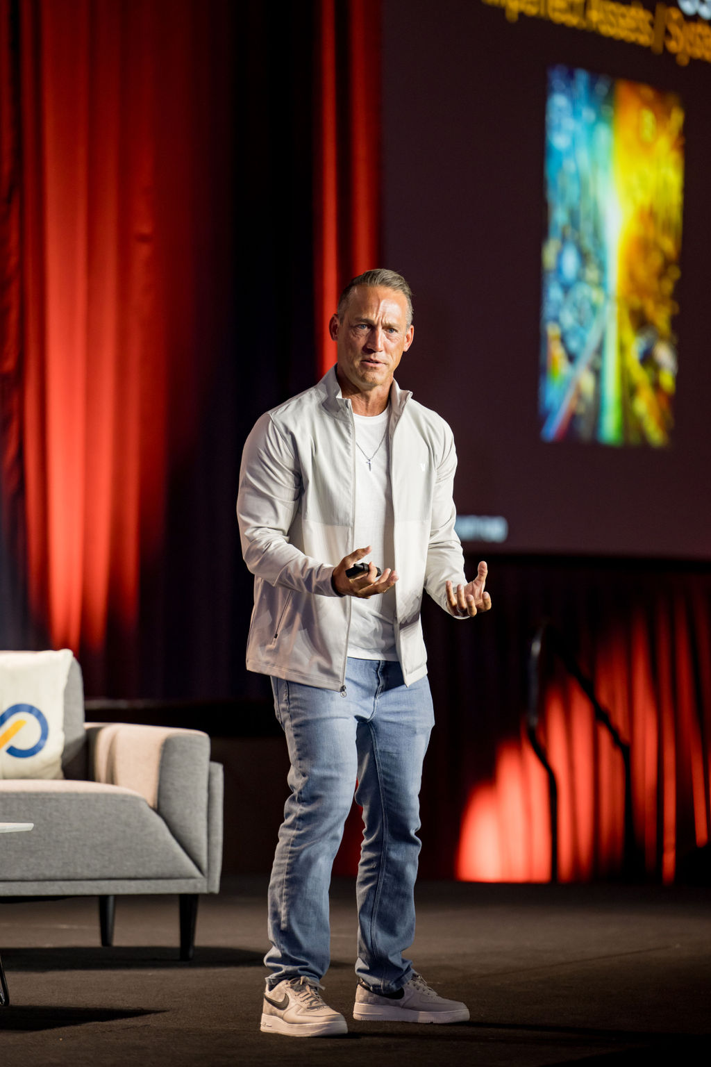 Speaker presenting to the room beside a lounge set on the Limitless Expo stage