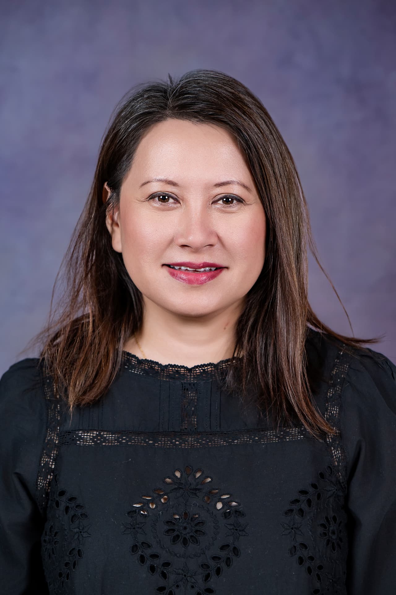 Studio headshot of a professional woman in a black lace blouse