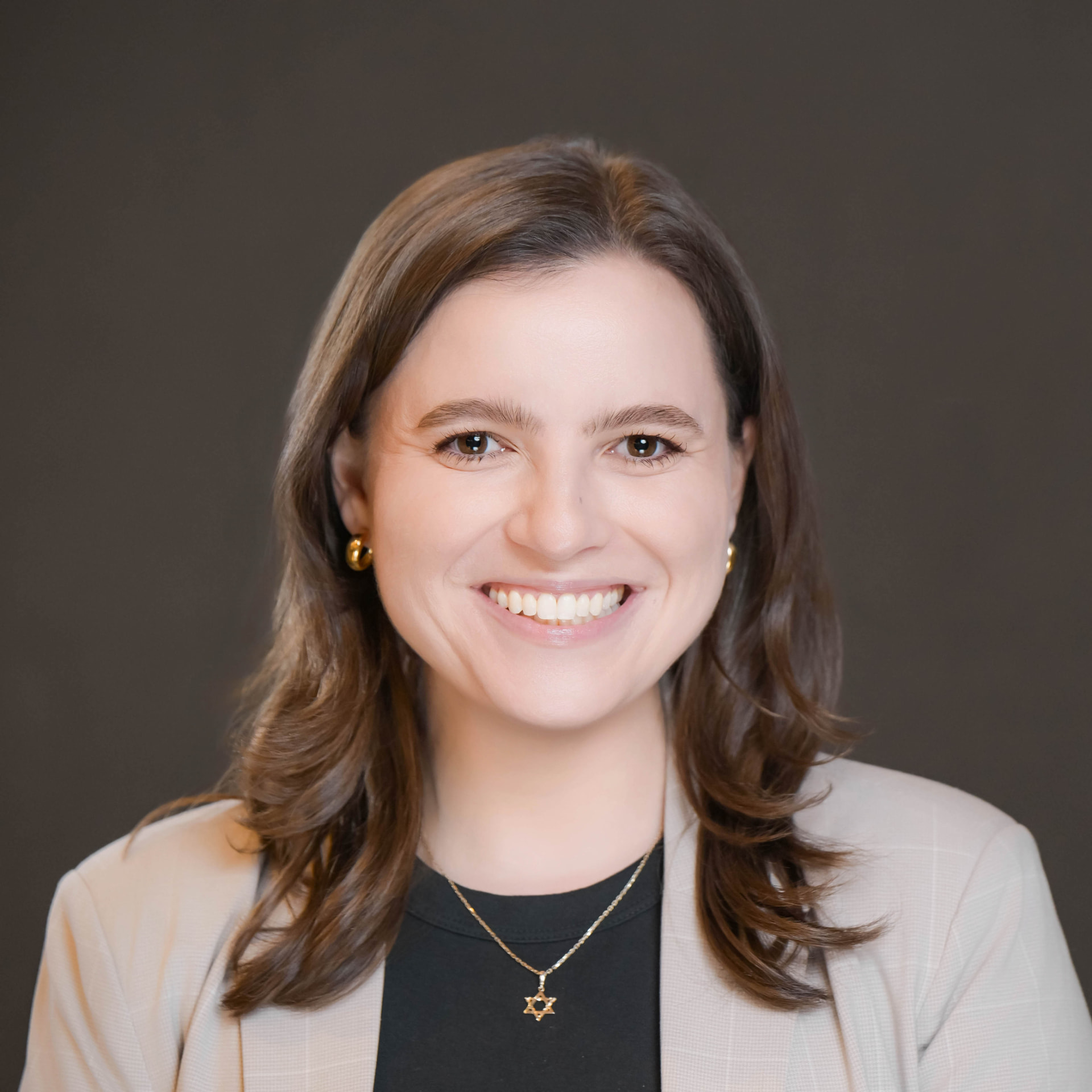 Studio headshot of a smiling professional woman in a cream blazer