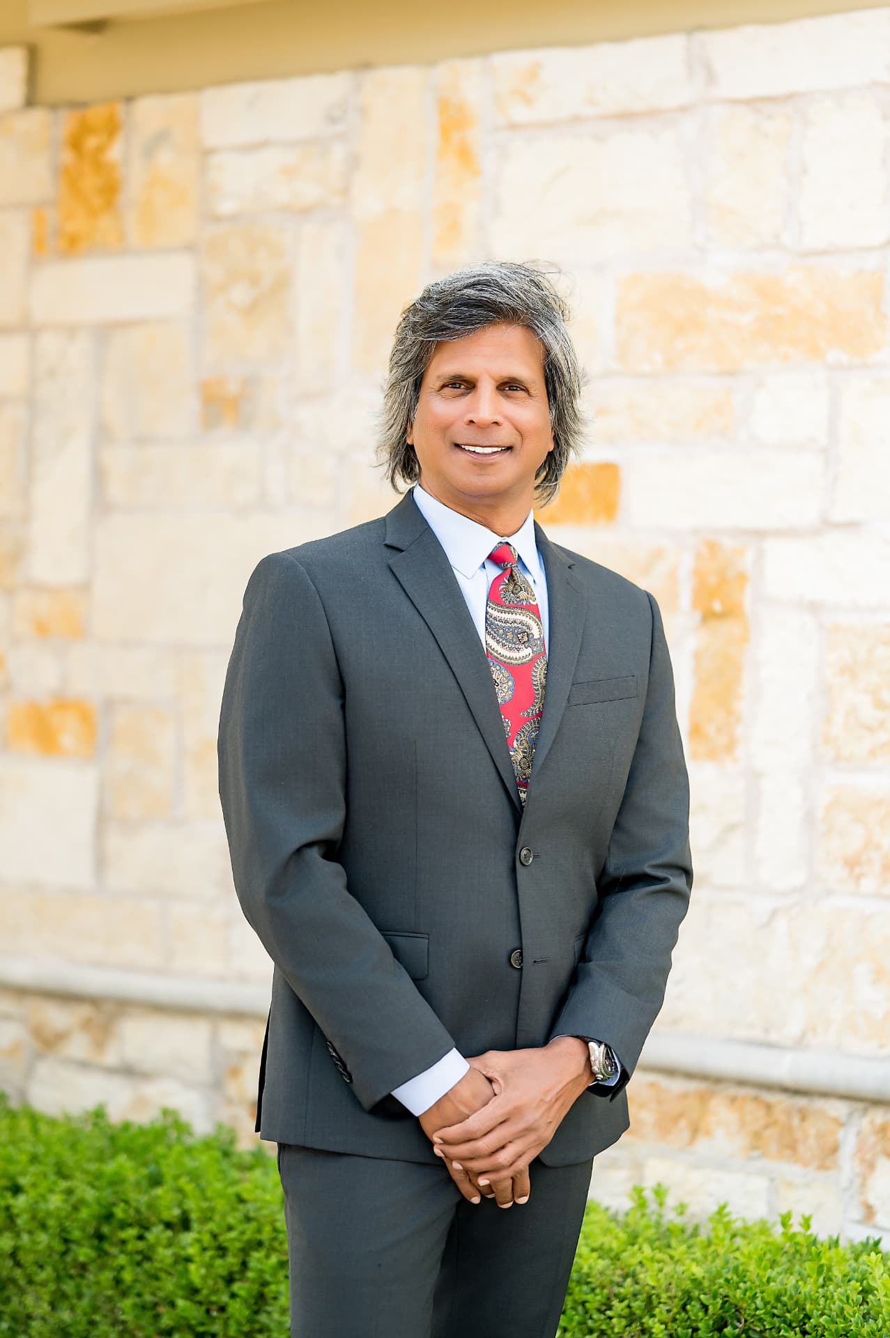 Business portrait of a man in a charcoal suit and red patterned tie