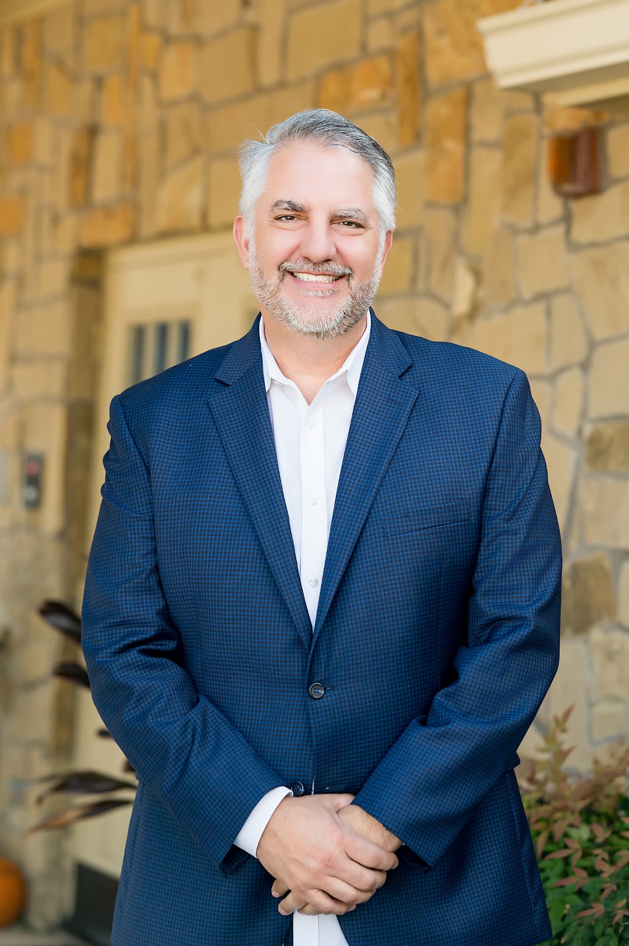Business portrait of a man in a navy check blazer outside a stone office building