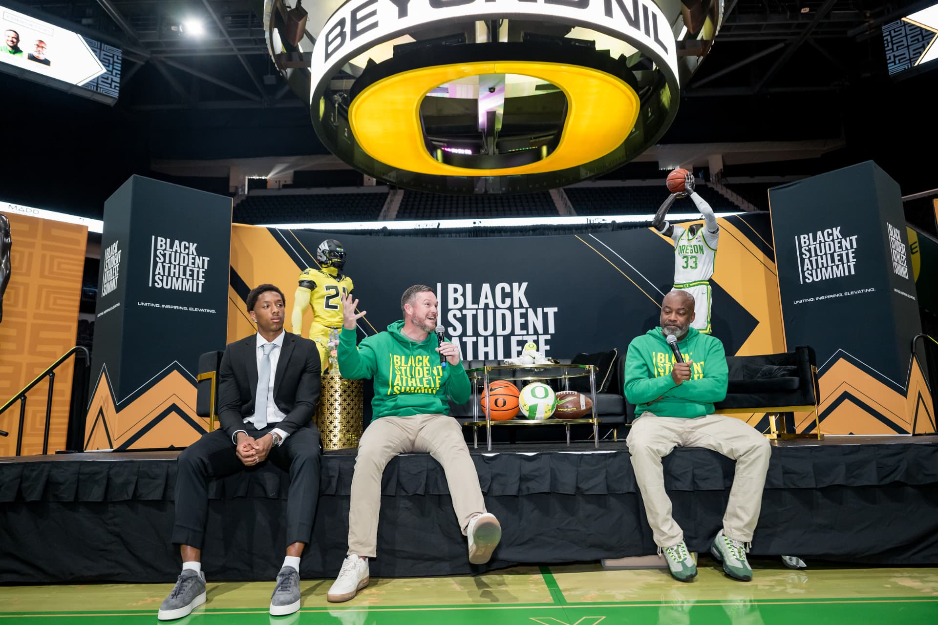 Panel discussion on stage beneath a large circular screen at the Black Student Athlete Summit in Eugene, Oregon