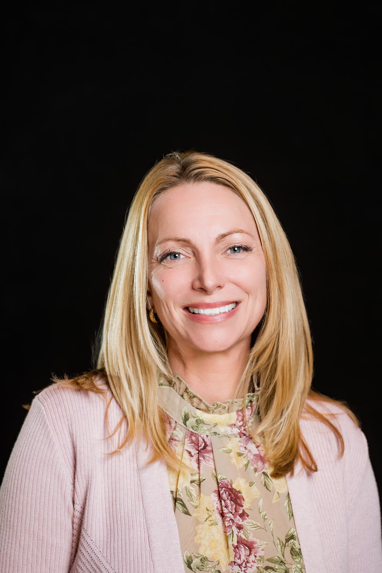 Studio headshot of a professional woman in a pink cardigan