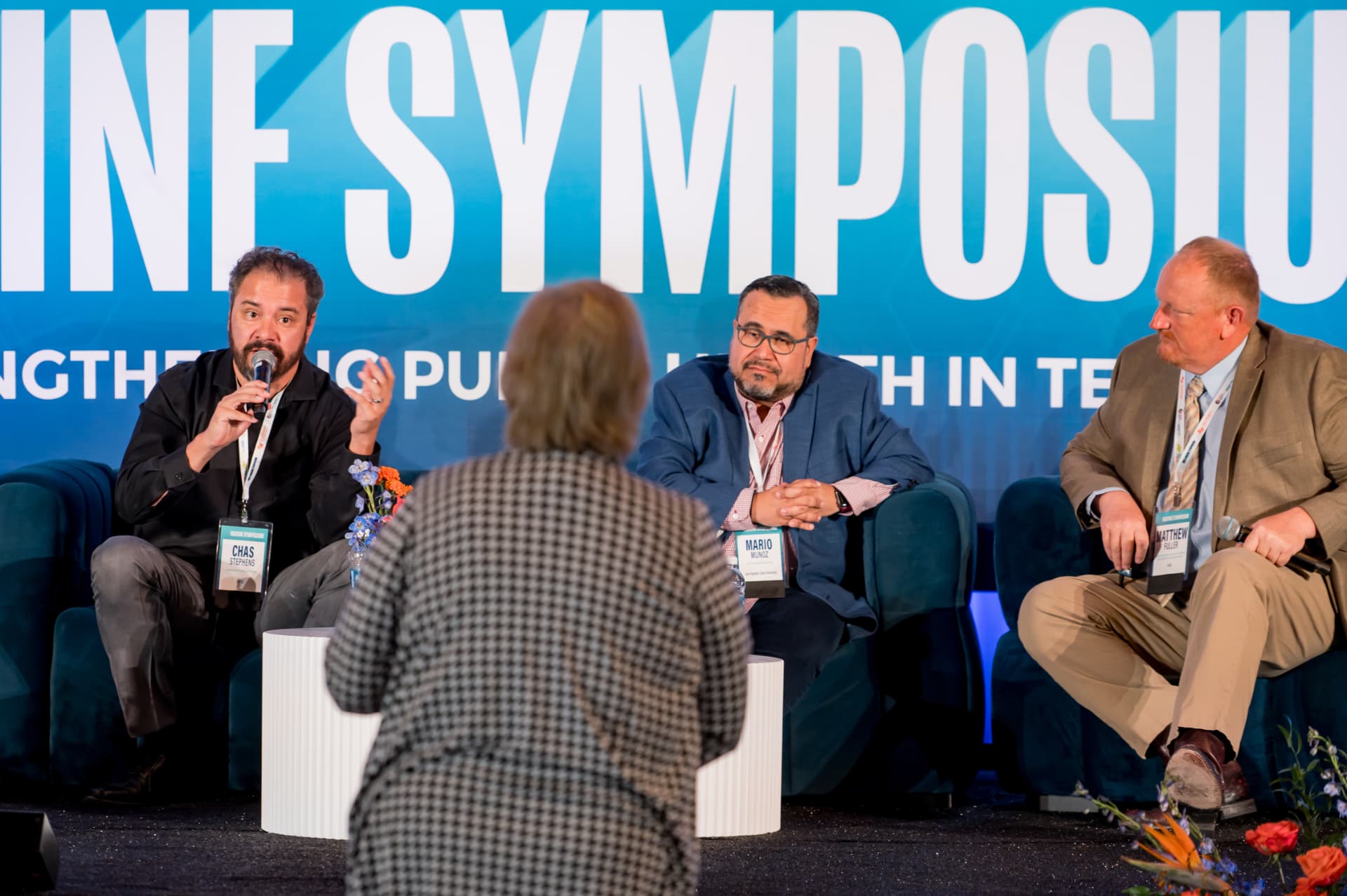 Panel discussion on stage taking a question from an audience member at a symposium