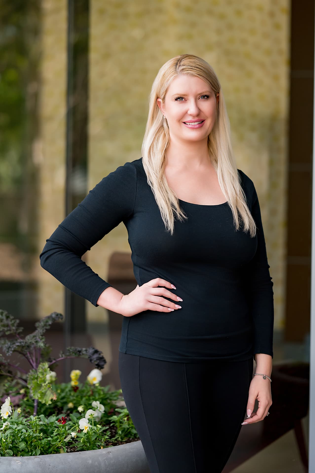 Business portrait of a woman in black beside a flower planter outside an office