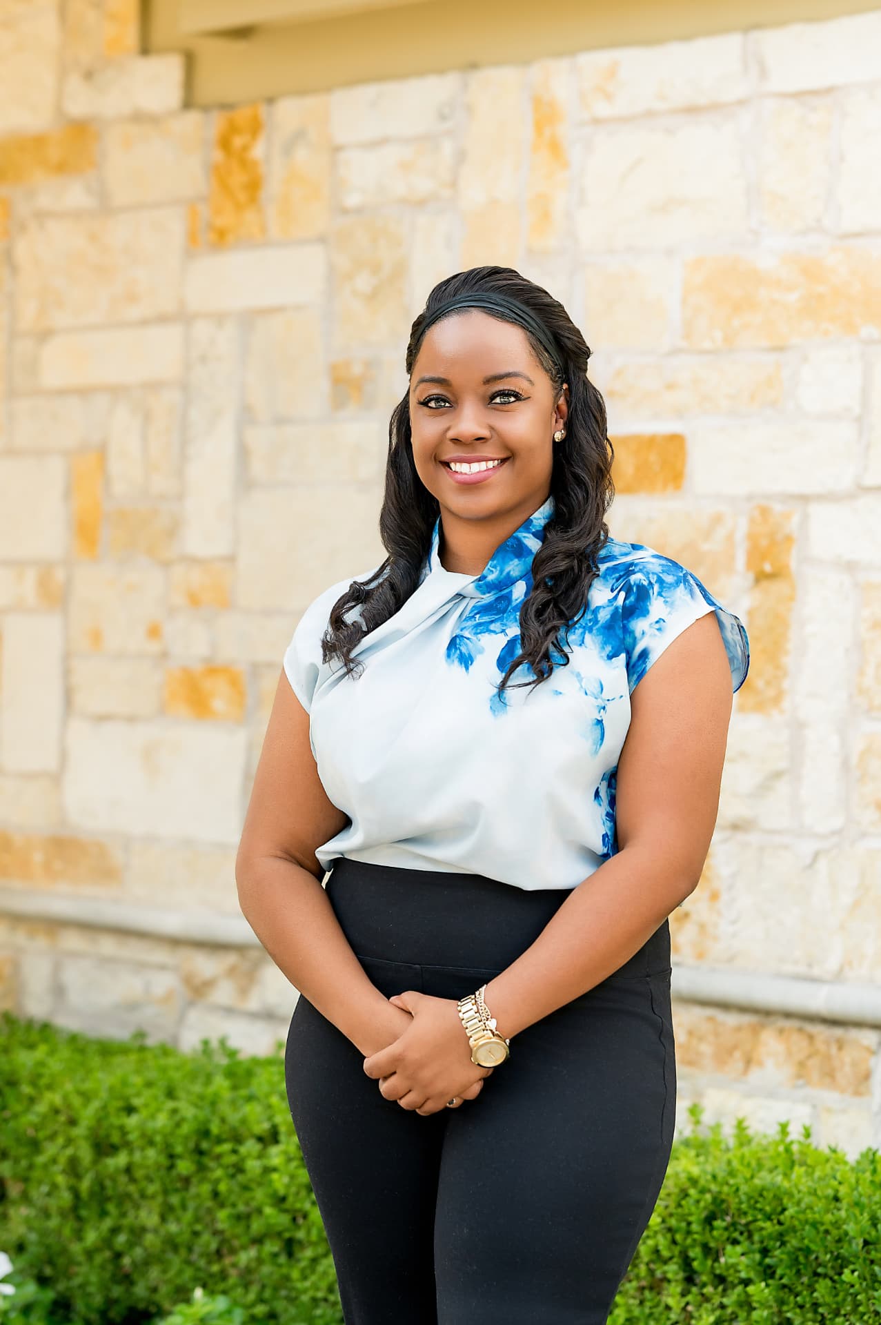 Business portrait of a woman in a blue floral blouse against a limestone wall