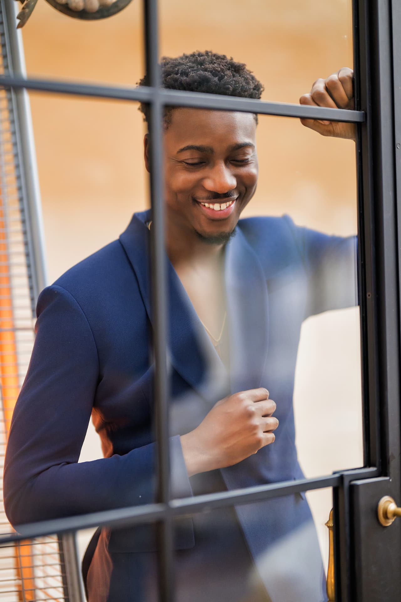 Smiling professional in a navy suit stepping through a glass door