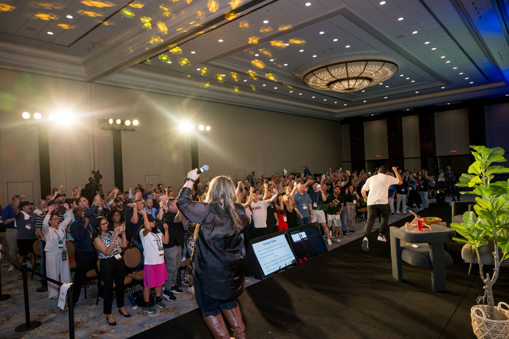 Crowd cheering with hands raised during a high-energy Limitless Expo moment