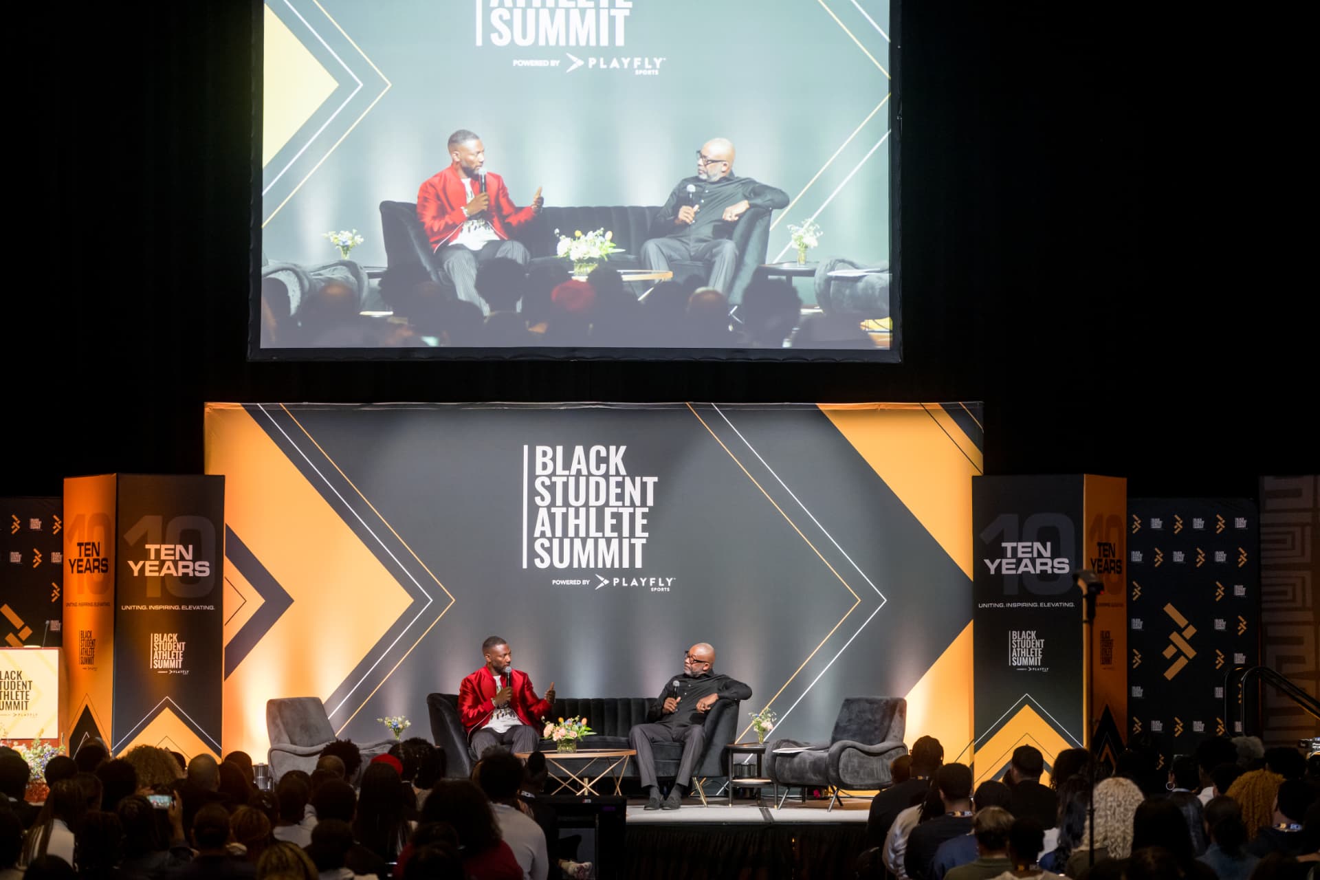 Wide view of the summit stage with the audience and projection screen