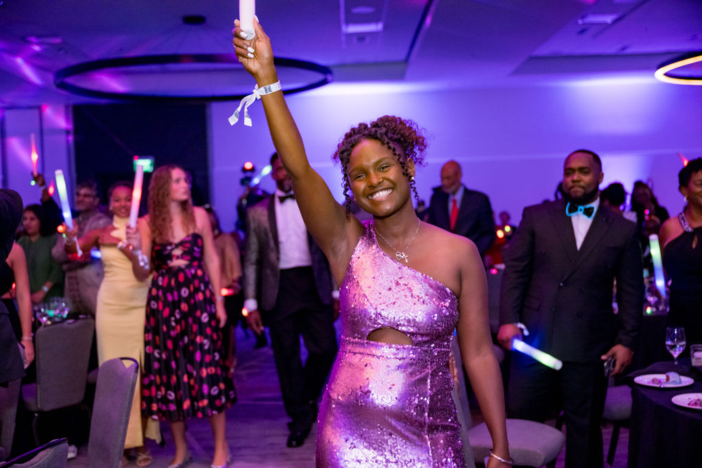 Guest in a sequined gown raising a glow stick