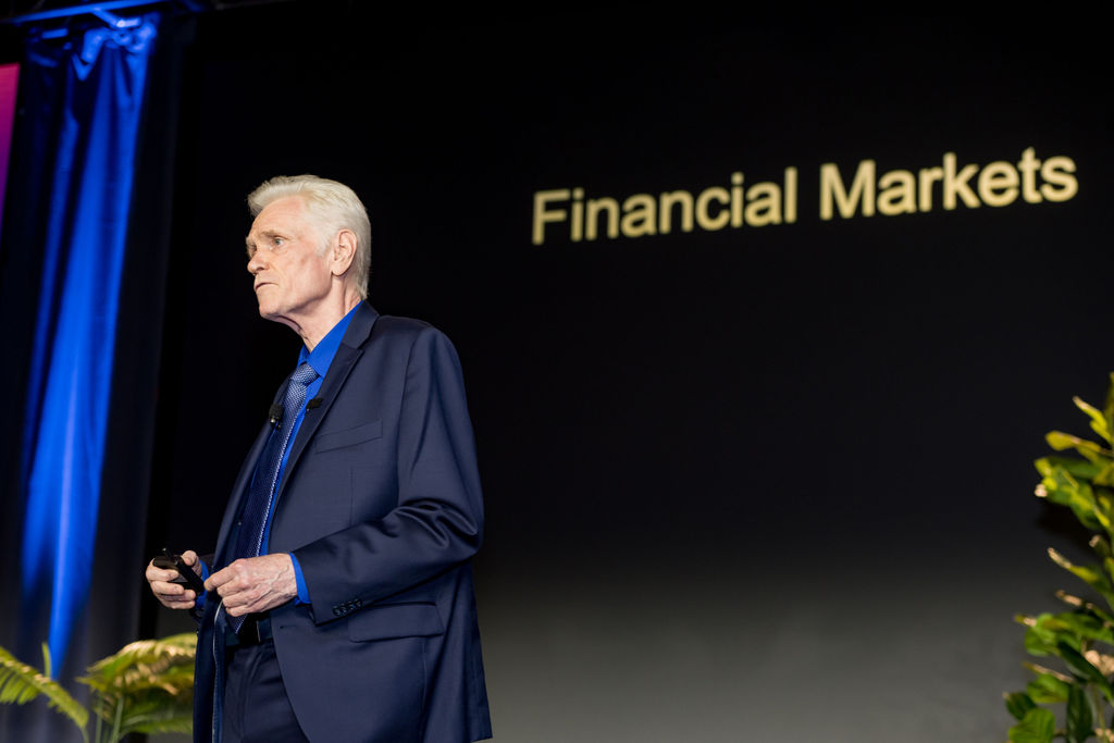 Speaker presenting a financial markets slide on the Limitless Expo main stage