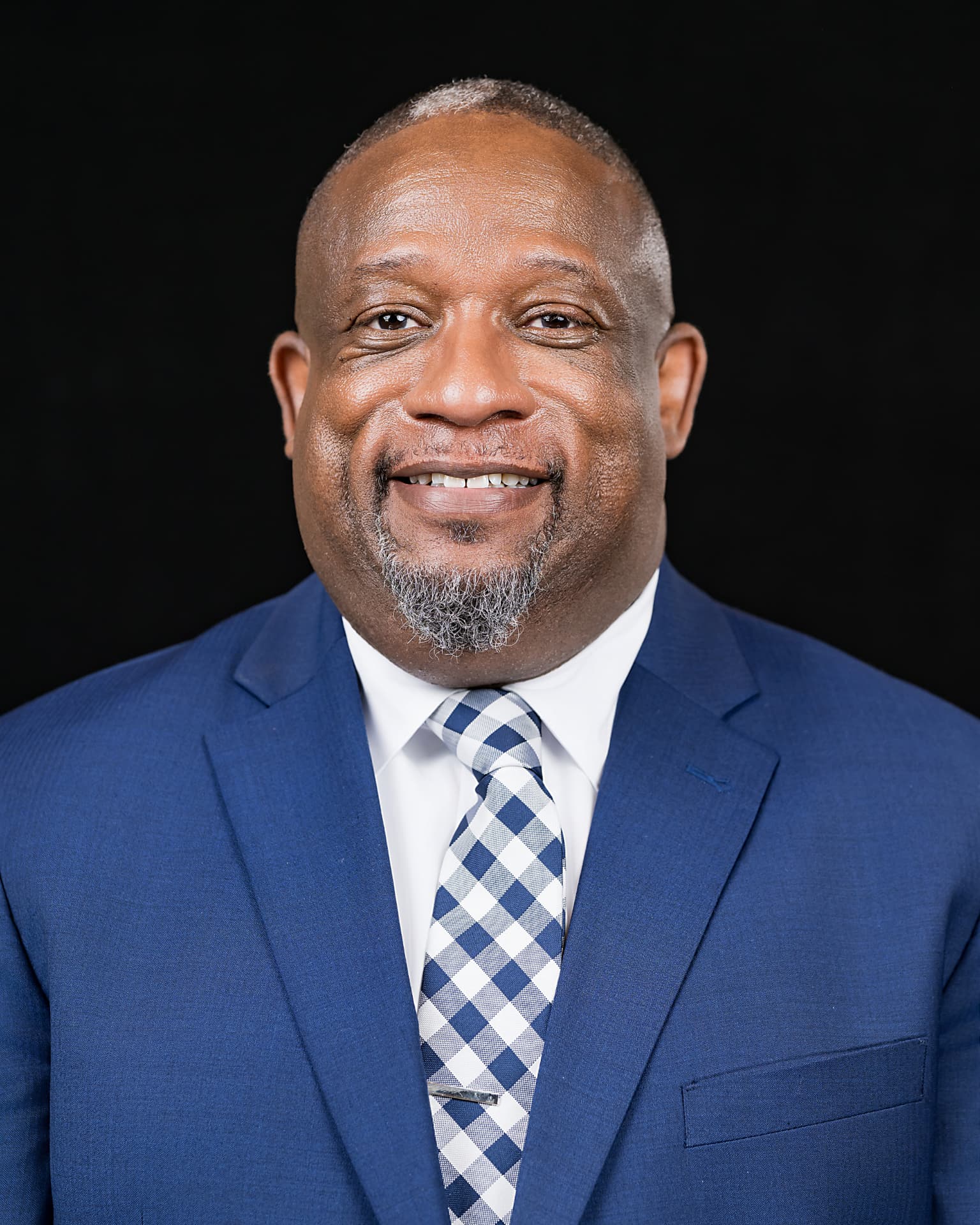 Studio headshot of a professional man in a blue suit and checked tie