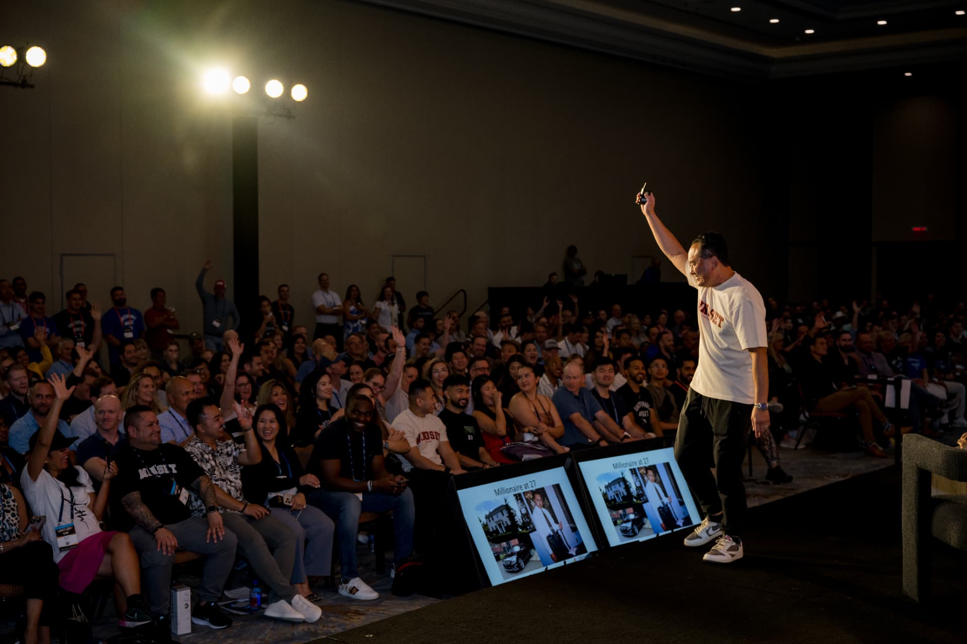 Keynote speaker on stage raising a hand to a cheering conference audience