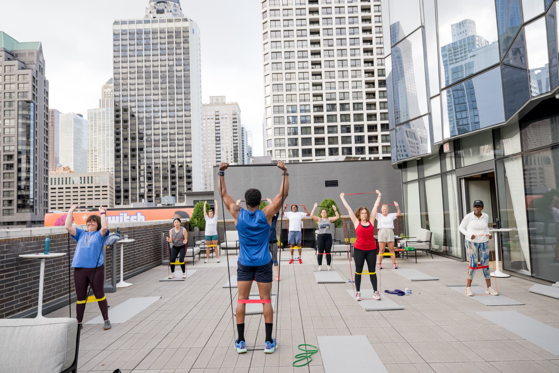 Corporate wellness group doing resistance-band training on a rooftop with the city skyline